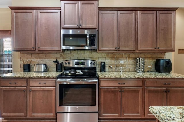 kitchen with stainless steel appliances, tasteful backsplash, and light stone countertops