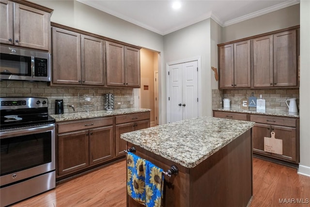 kitchen with light wood-style floors, tasteful backsplash, stainless steel appliances, and crown molding