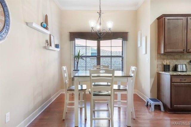 dining space featuring a chandelier, dark wood-type flooring, ornamental molding, and baseboards