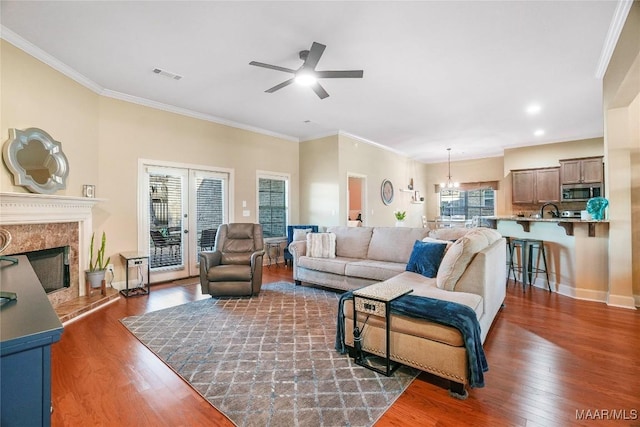 living area with ornamental molding, wood finished floors, visible vents, and a high end fireplace