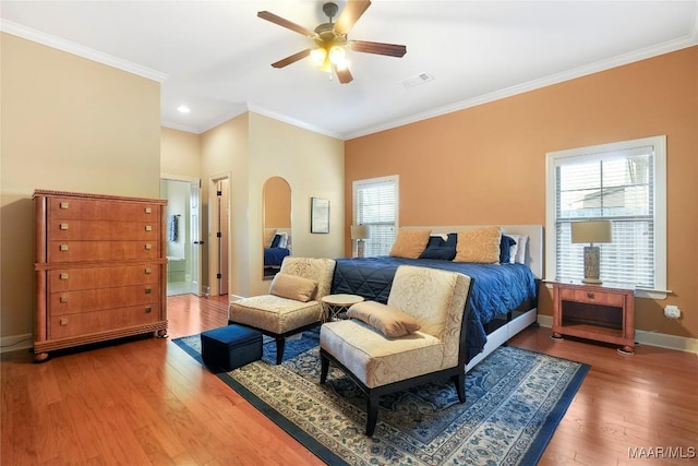 bedroom featuring arched walkways, multiple windows, wood finished floors, and visible vents