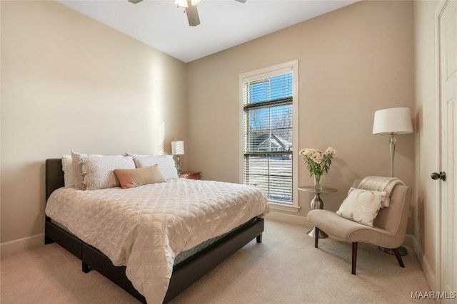 bedroom with a ceiling fan, light carpet, and baseboards