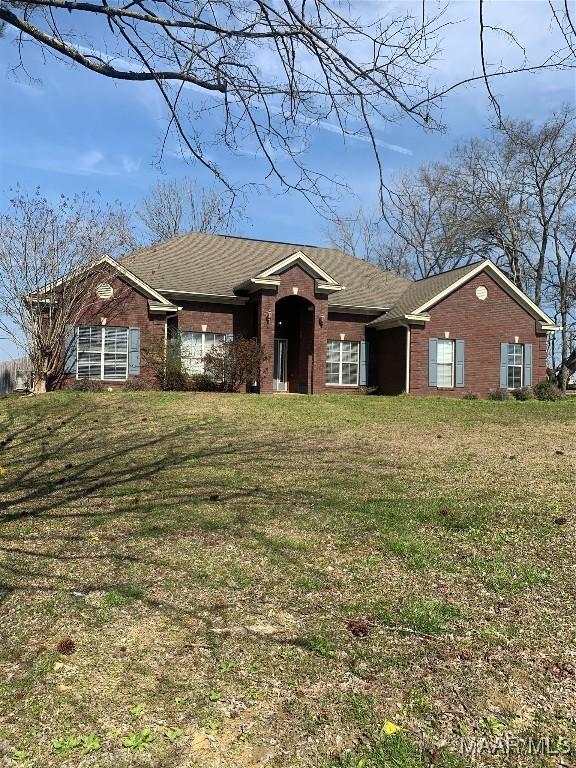 single story home with roof with shingles, brick siding, and a front lawn