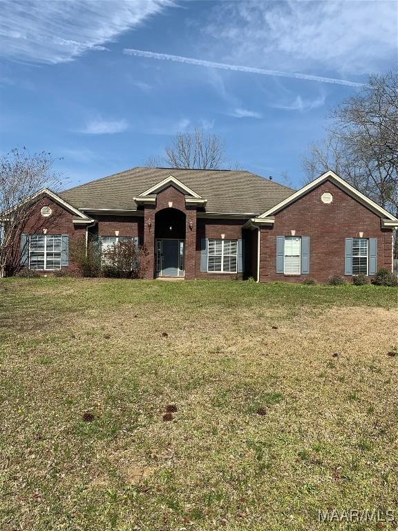 ranch-style house with a front yard, brick siding, and roof with shingles