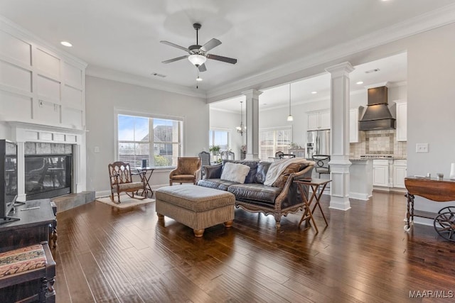 living room with ornate columns, dark wood-style floors, and a tile fireplace