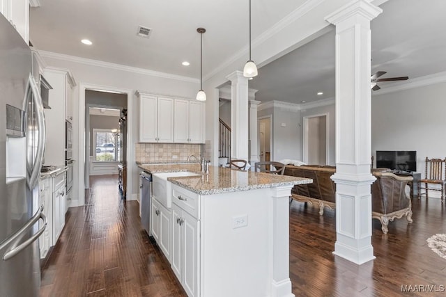 kitchen featuring appliances with stainless steel finishes, open floor plan, white cabinets, and ornate columns