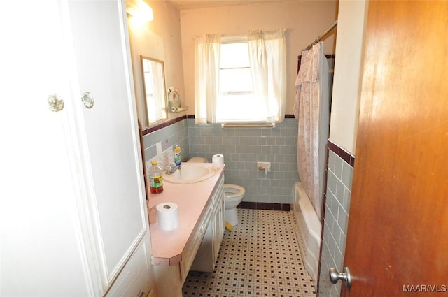 full bathroom with tile walls, toilet, wainscoting, vanity, and tile patterned floors