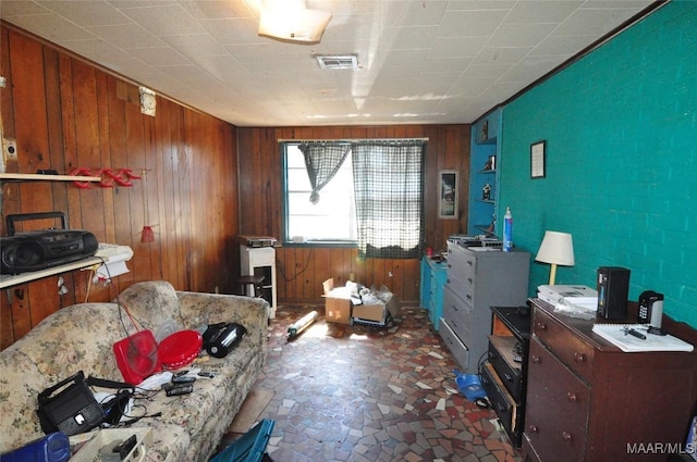 miscellaneous room featuring stone finish floor, wooden walls, and visible vents