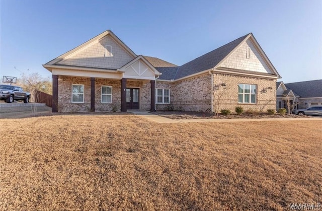 craftsman inspired home featuring french doors, brick siding, and a front lawn