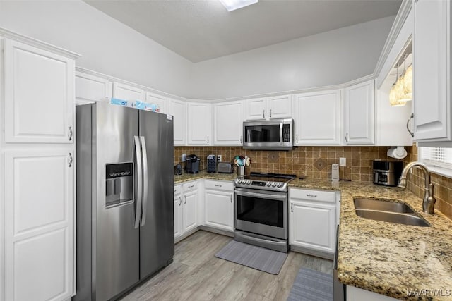 kitchen with stainless steel appliances, a sink, white cabinetry, and decorative backsplash