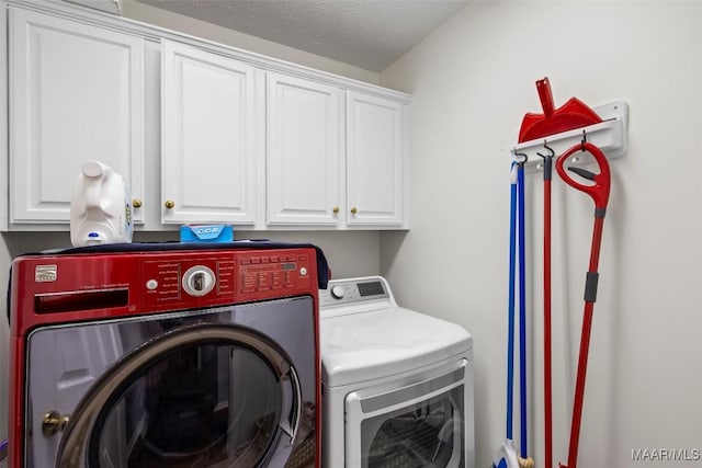 washroom with a textured ceiling, washing machine and dryer, and cabinet space