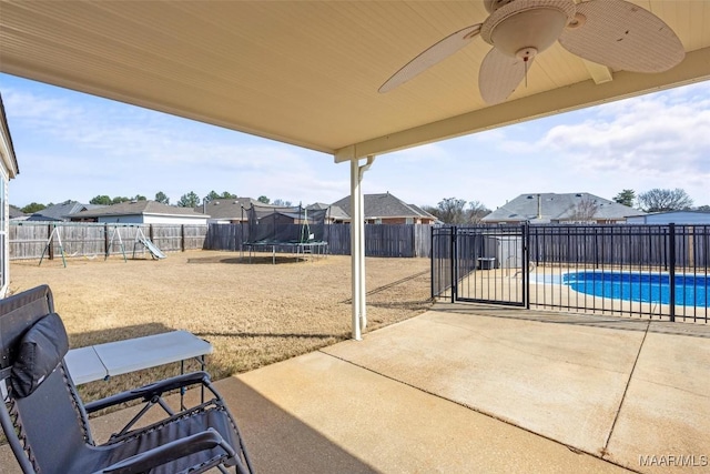 view of patio with a trampoline, a fenced in pool, a playground, ceiling fan, and a fenced backyard