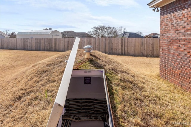 view of storm shelter featuring fence and a lawn