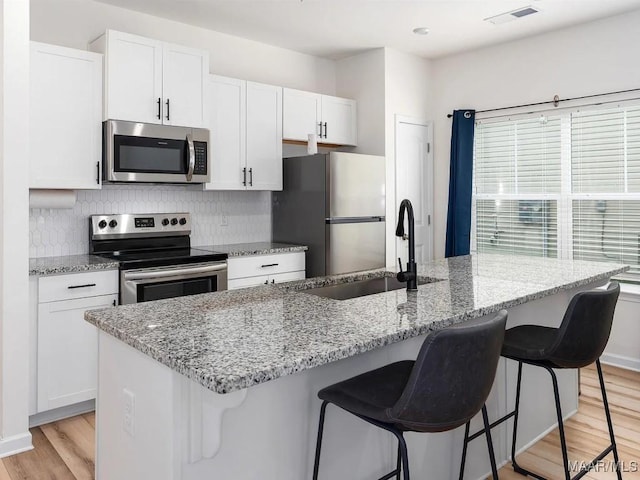 kitchen with white cabinets, light wood-type flooring, visible vents, and stainless steel appliances