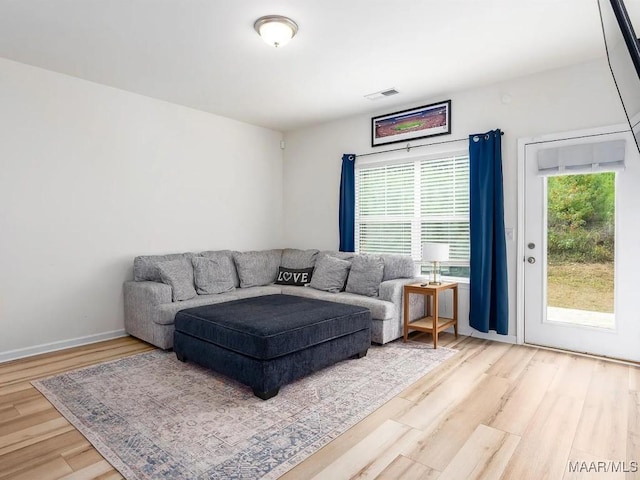 living area with plenty of natural light, wood finished floors, visible vents, and baseboards