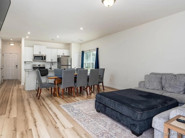 dining area featuring recessed lighting, light wood-style flooring, and baseboards