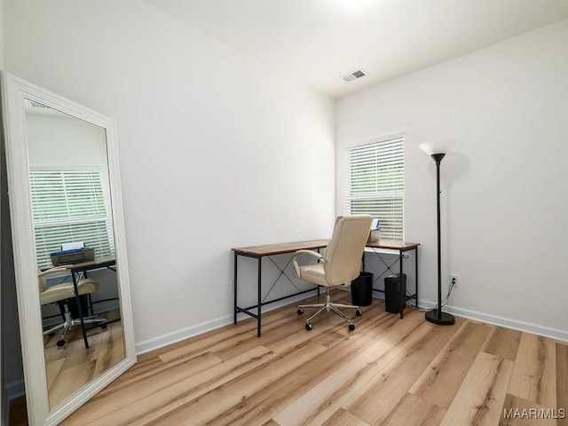 office area featuring a wealth of natural light, visible vents, baseboards, and wood finished floors