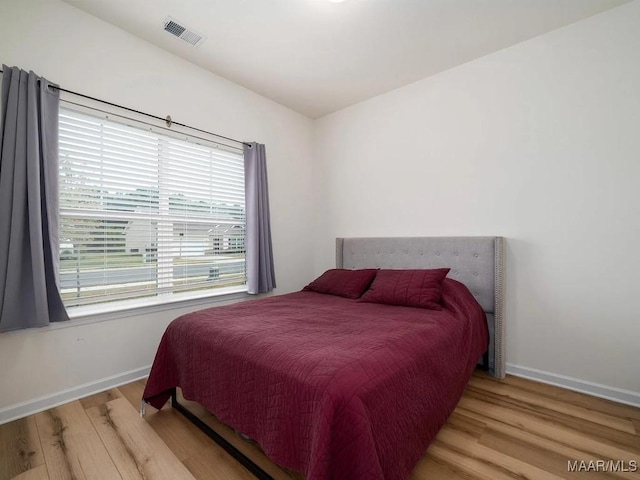 bedroom with wood finished floors, visible vents, and baseboards