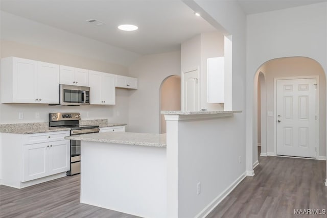 kitchen with appliances with stainless steel finishes, dark wood-type flooring, white cabinetry, and light stone countertops