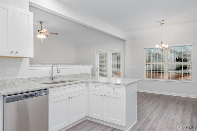 kitchen with a peninsula, a sink, white cabinets, stainless steel dishwasher, and light stone countertops