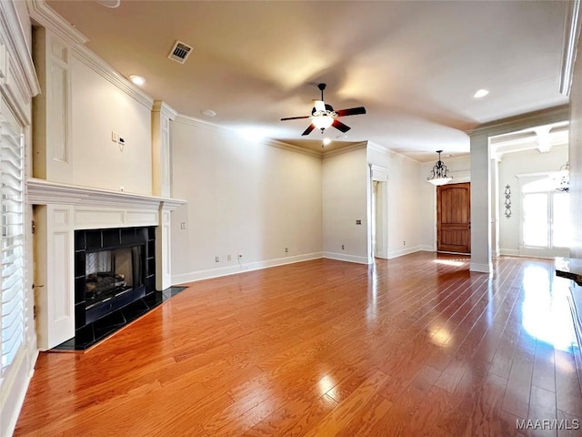 unfurnished living room with visible vents, a tile fireplace, ceiling fan, wood finished floors, and crown molding