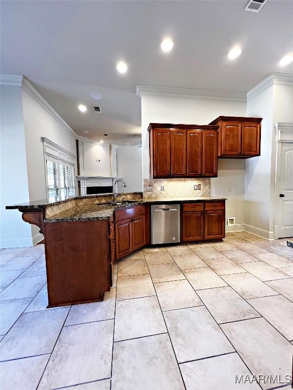 kitchen with ornamental molding, a peninsula, stainless steel dishwasher, and a sink