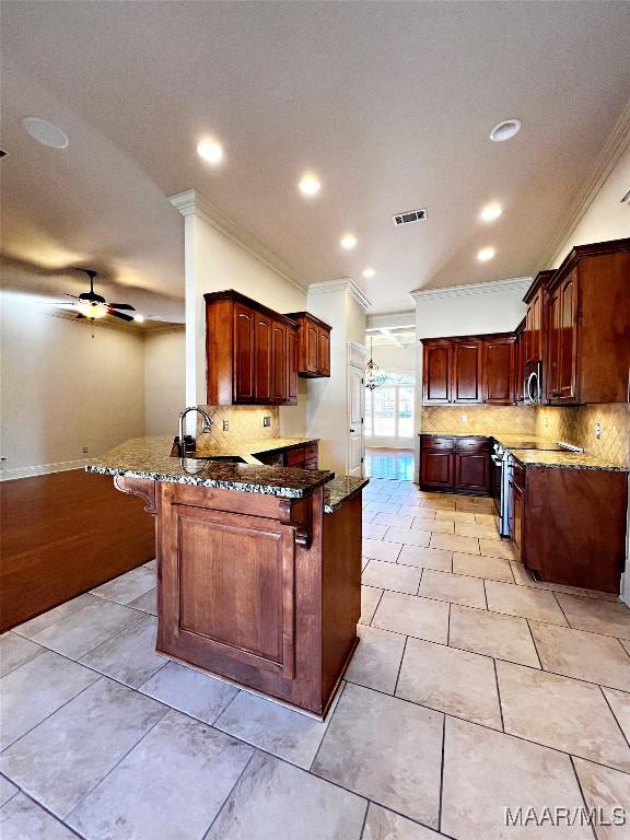 kitchen featuring visible vents, appliances with stainless steel finishes, a sink, dark stone countertops, and a peninsula