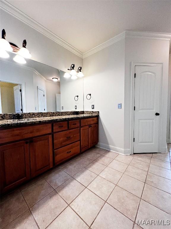 bathroom with baseboards, double vanity, ornamental molding, and tile patterned floors