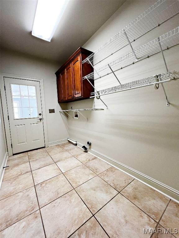 laundry room featuring light tile patterned floors, baseboards, cabinet space, and hookup for a gas dryer