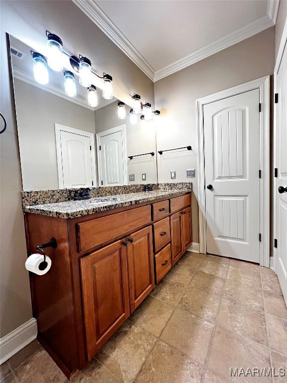 bathroom featuring double vanity, visible vents, ornamental molding, and baseboards