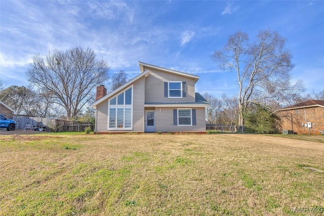 view of front of home with a chimney, fence, and a front yard