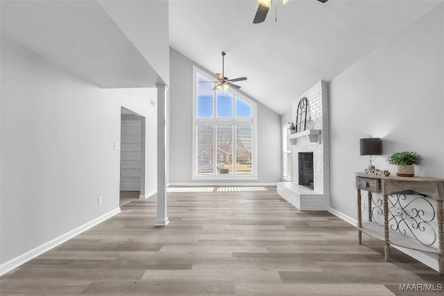 living area featuring baseboards, a ceiling fan, wood finished floors, a fireplace, and high vaulted ceiling