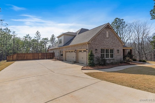 view of side of property featuring driveway, a lawn, an attached garage, fence, and brick siding