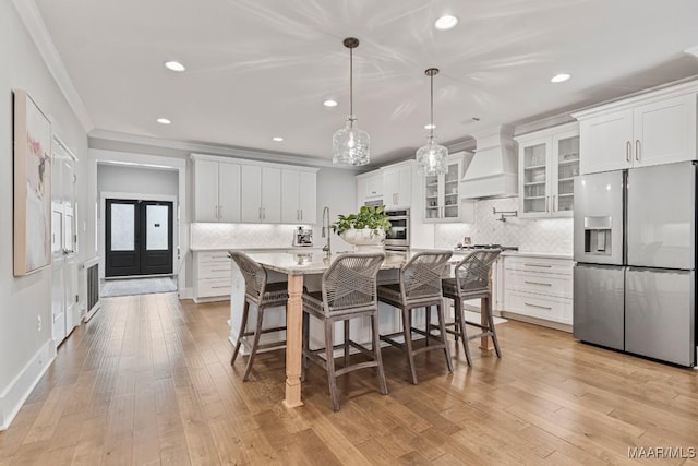 kitchen featuring appliances with stainless steel finishes, white cabinets, premium range hood, and ornamental molding