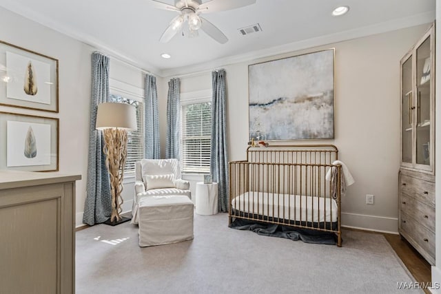 carpeted bedroom featuring a crib, recessed lighting, visible vents, and baseboards