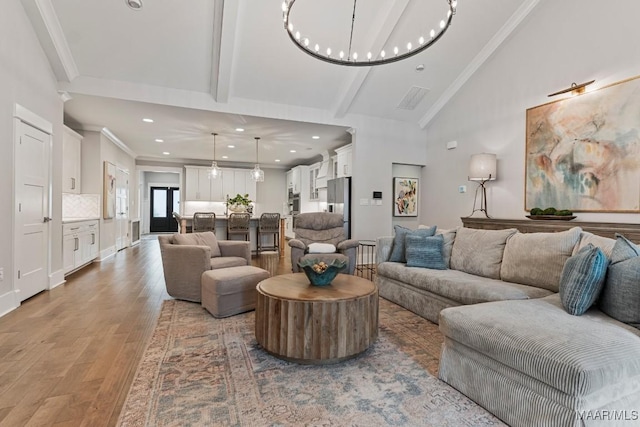 living room featuring beam ceiling, a notable chandelier, crown molding, light wood-style flooring, and high vaulted ceiling