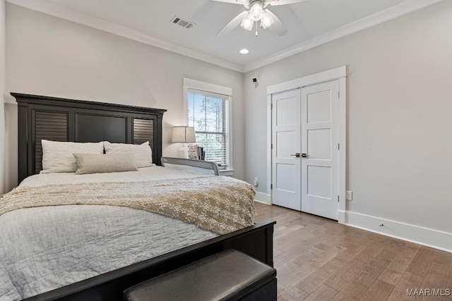 bedroom featuring wood finished floors, a ceiling fan, baseboards, visible vents, and crown molding