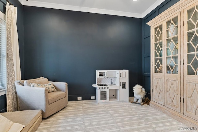 sitting room with ornamental molding and carpet flooring