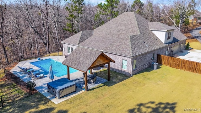 exterior space with a patio area, a jacuzzi, fence, and a lawn