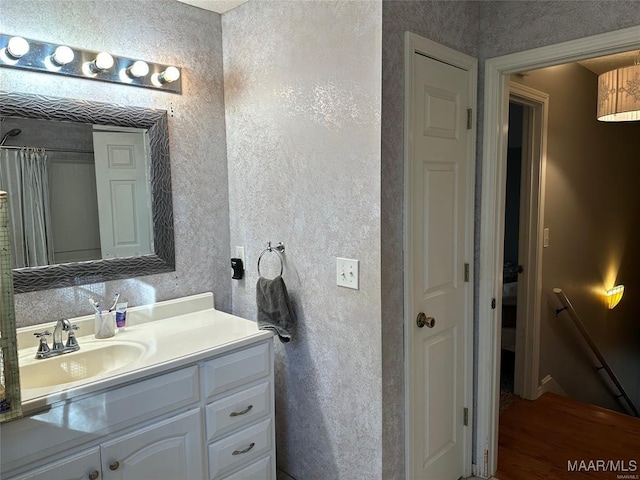 full bath featuring a shower with curtain, vanity, and a textured wall