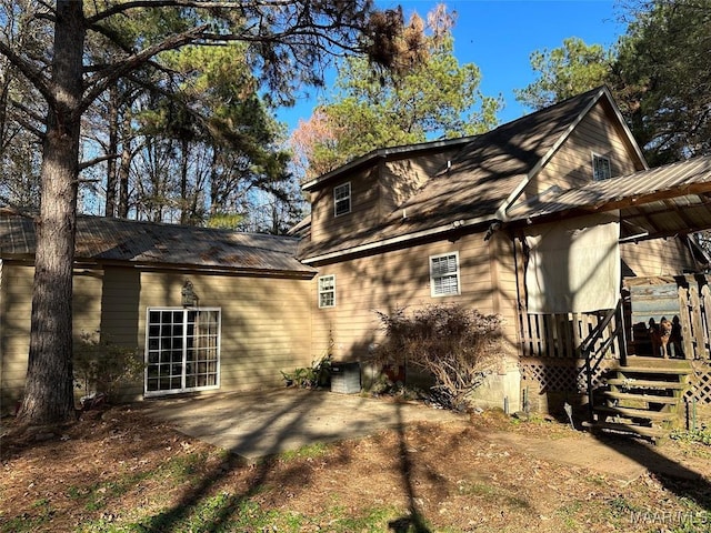 view of side of home with metal roof and a patio