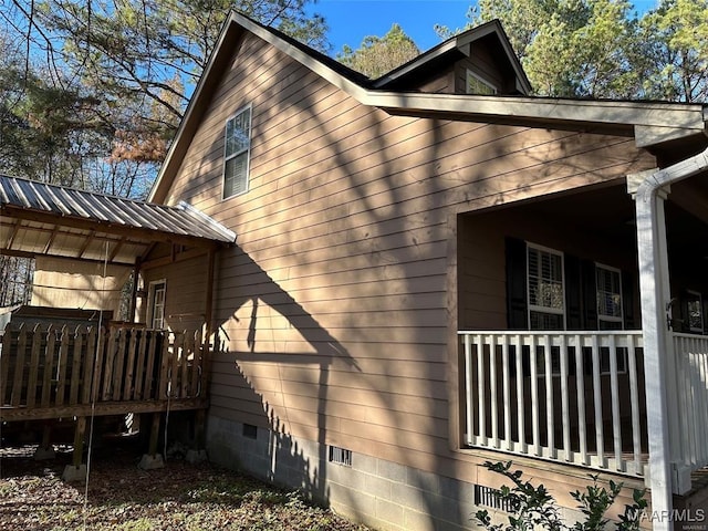 view of home's exterior featuring crawl space, covered porch, and metal roof