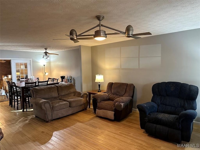 living room featuring a textured ceiling, light wood finished floors, and a ceiling fan