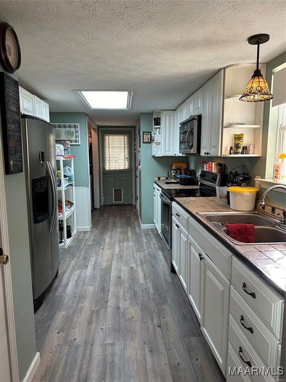 kitchen with white cabinetry, appliances with stainless steel finishes, a sink, and open shelves