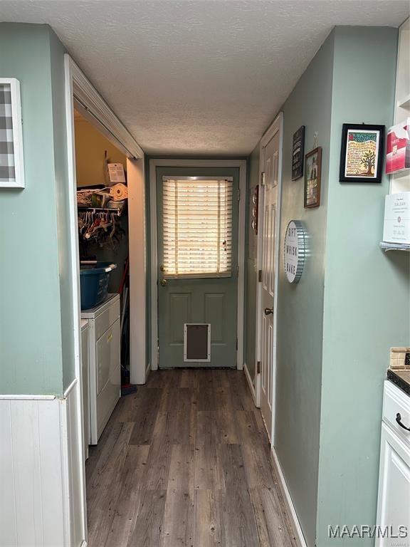 doorway with washing machine and clothes dryer, wood finished floors, and a textured ceiling