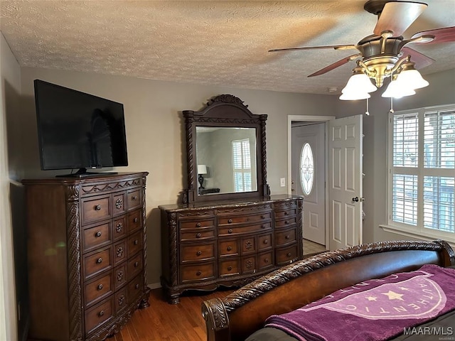 bedroom with a textured ceiling, a ceiling fan, and wood finished floors