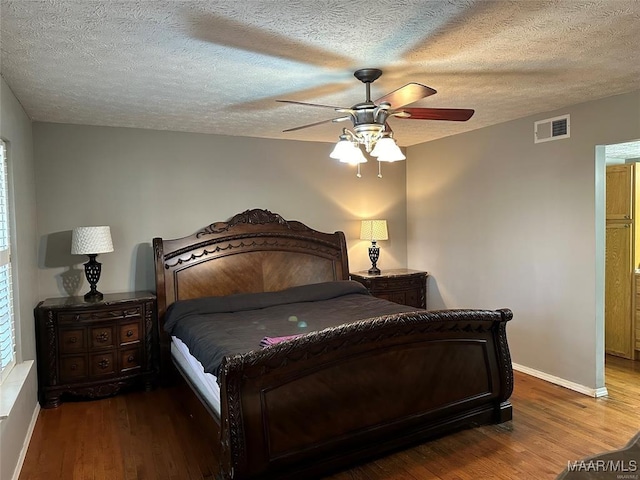 bedroom with visible vents, baseboards, wood finished floors, and a textured ceiling