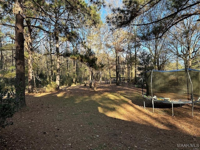 view of yard featuring a trampoline and fence