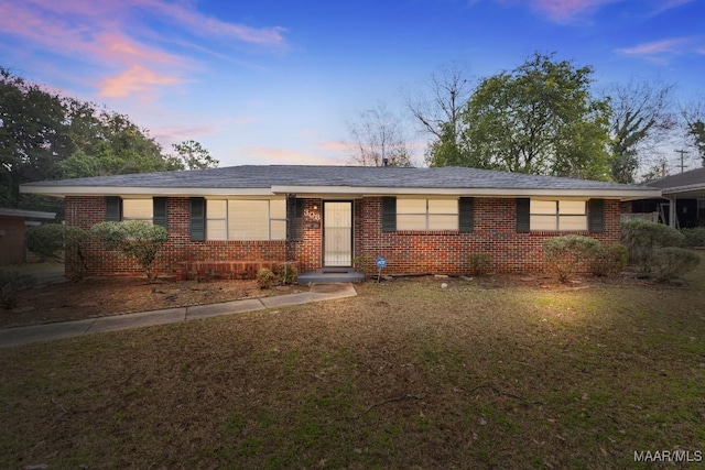 single story home with brick siding and a front yard