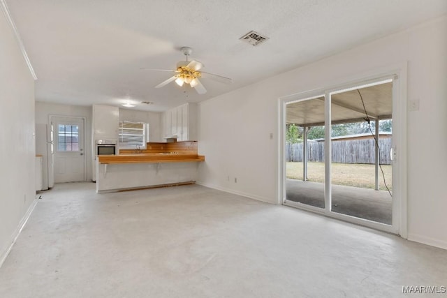 interior space featuring a ceiling fan, visible vents, concrete floors, and baseboards